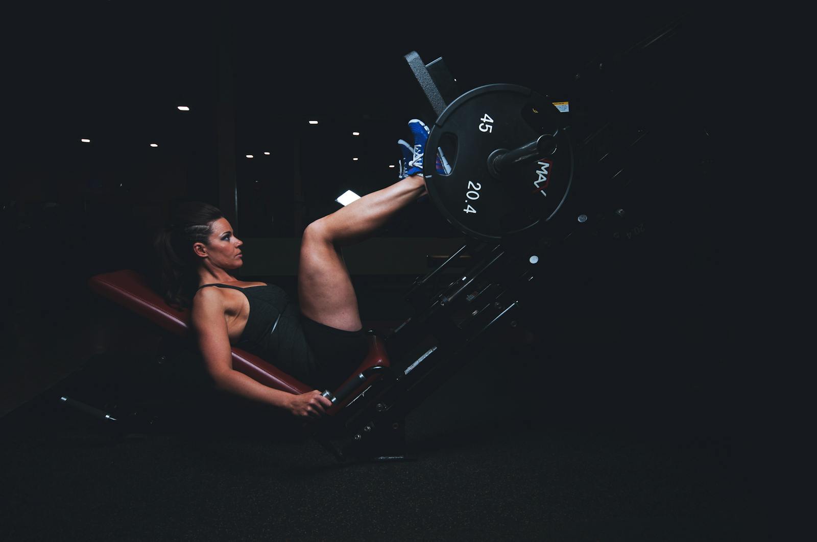 A woman engages in an intense leg press workout at the gym, showcasing strength and fitness.