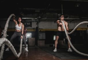 Two people engage in a powerful indoor battle rope workout, showcasing strength and energy.