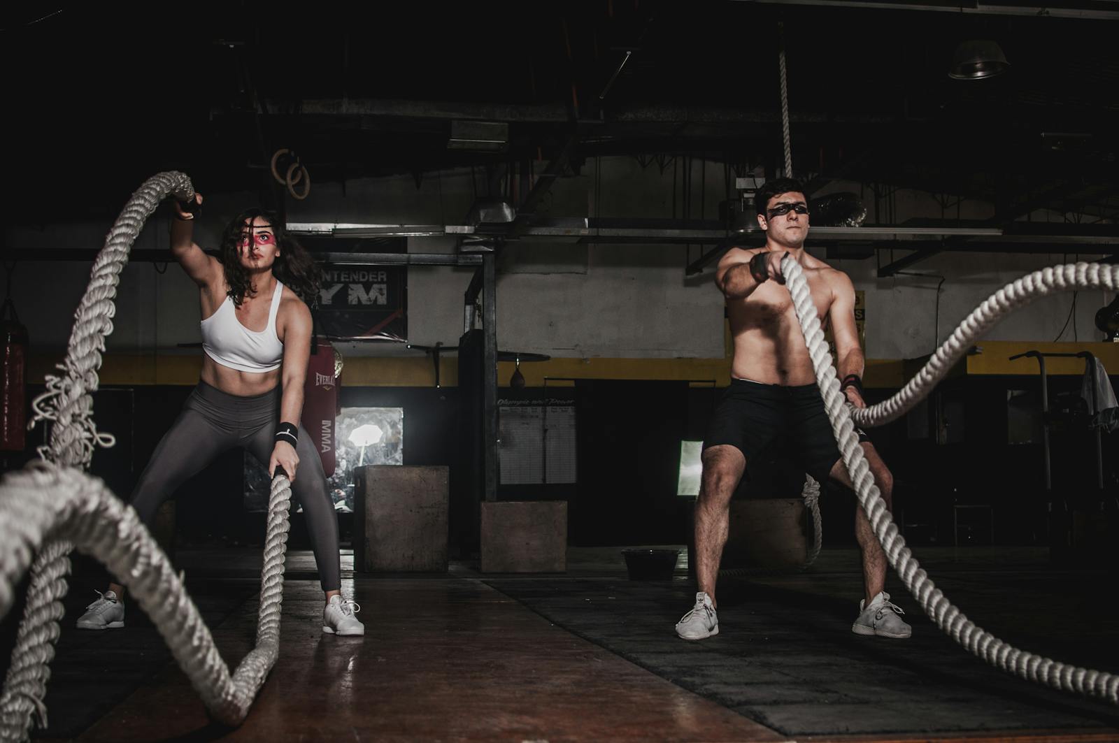 Two people engage in a powerful indoor battle rope workout, showcasing strength and energy.