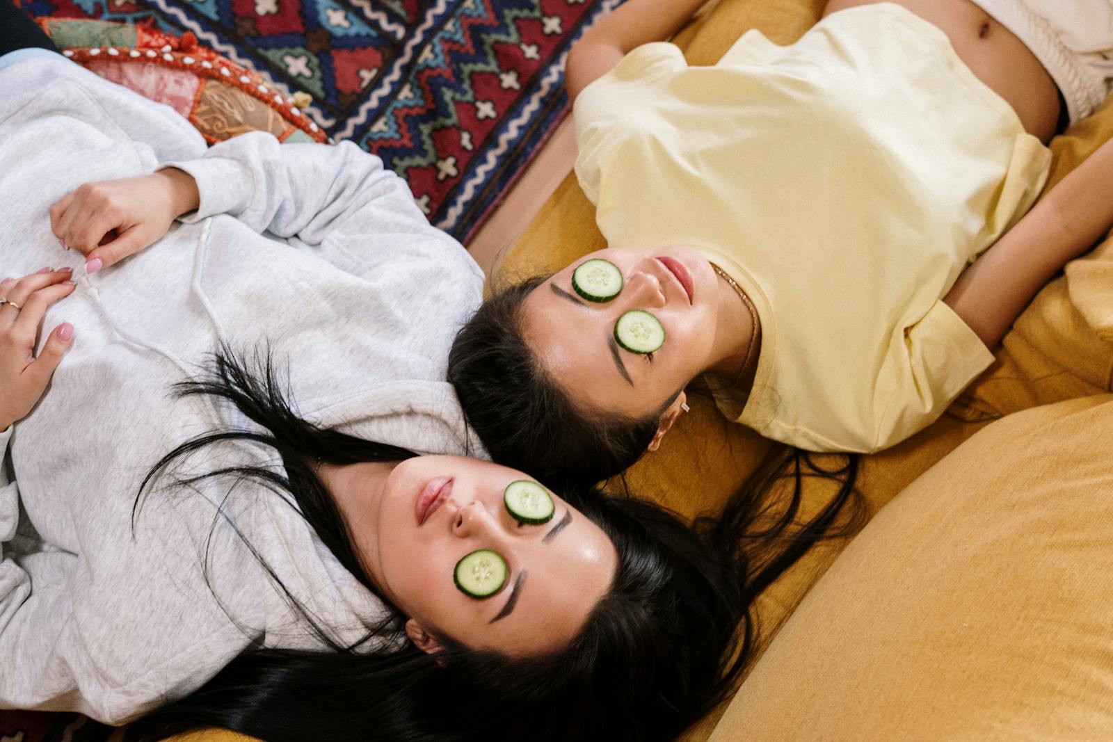 Two friends relaxing at home with cucumber masks in a cozy setting, enjoying a DIY skincare session.