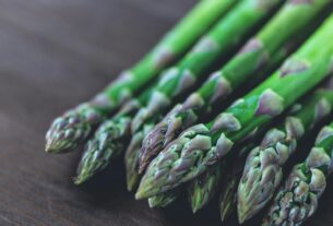 Close-up of fresh green asparagus spears displayed on a rustic wooden table.