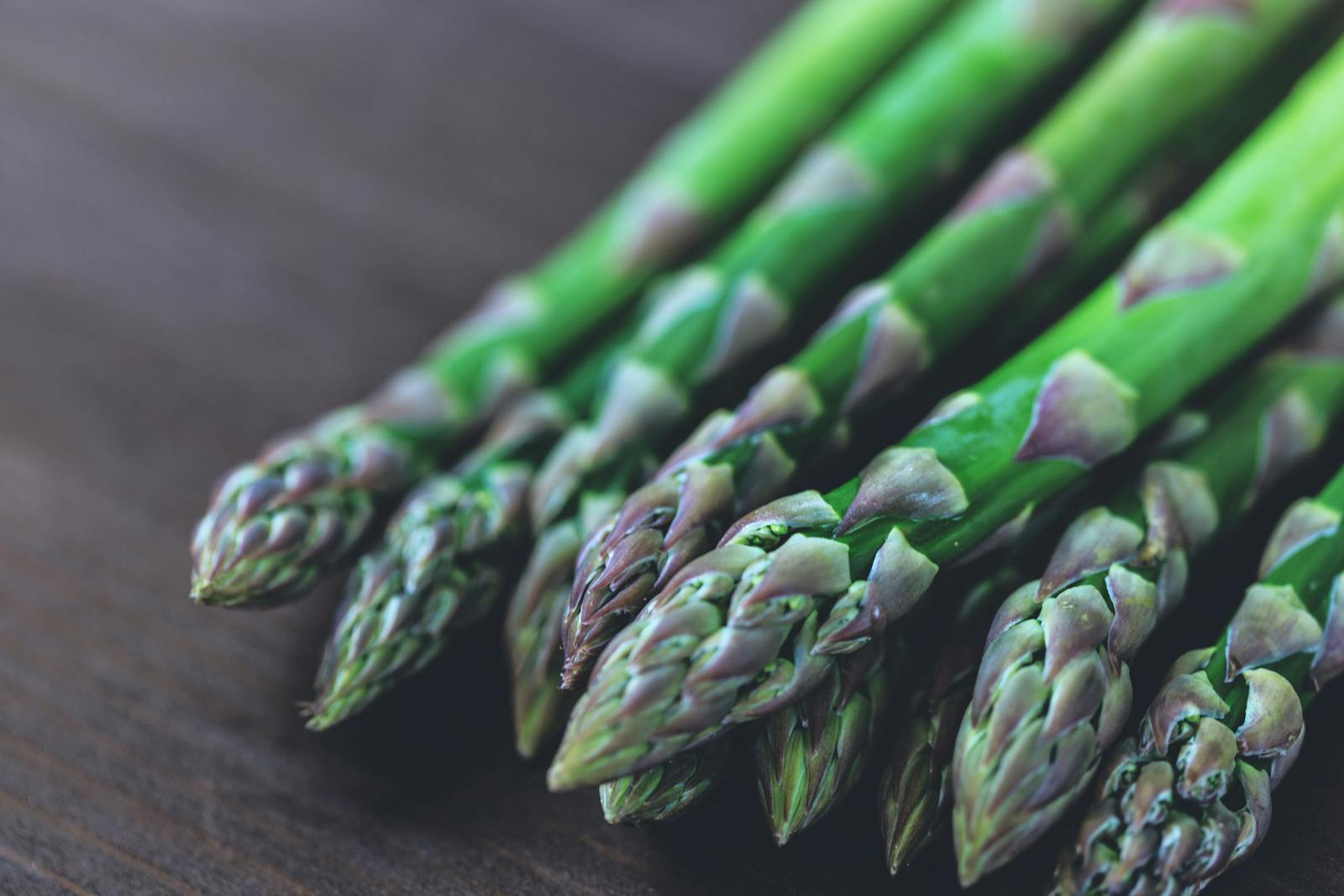 Close-up of fresh green asparagus spears displayed on a rustic wooden table.