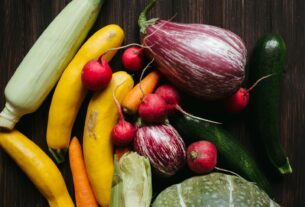 A vivid array of fresh vegetables on a dark wooden table, showcasing a healthy, organic lifestyle.