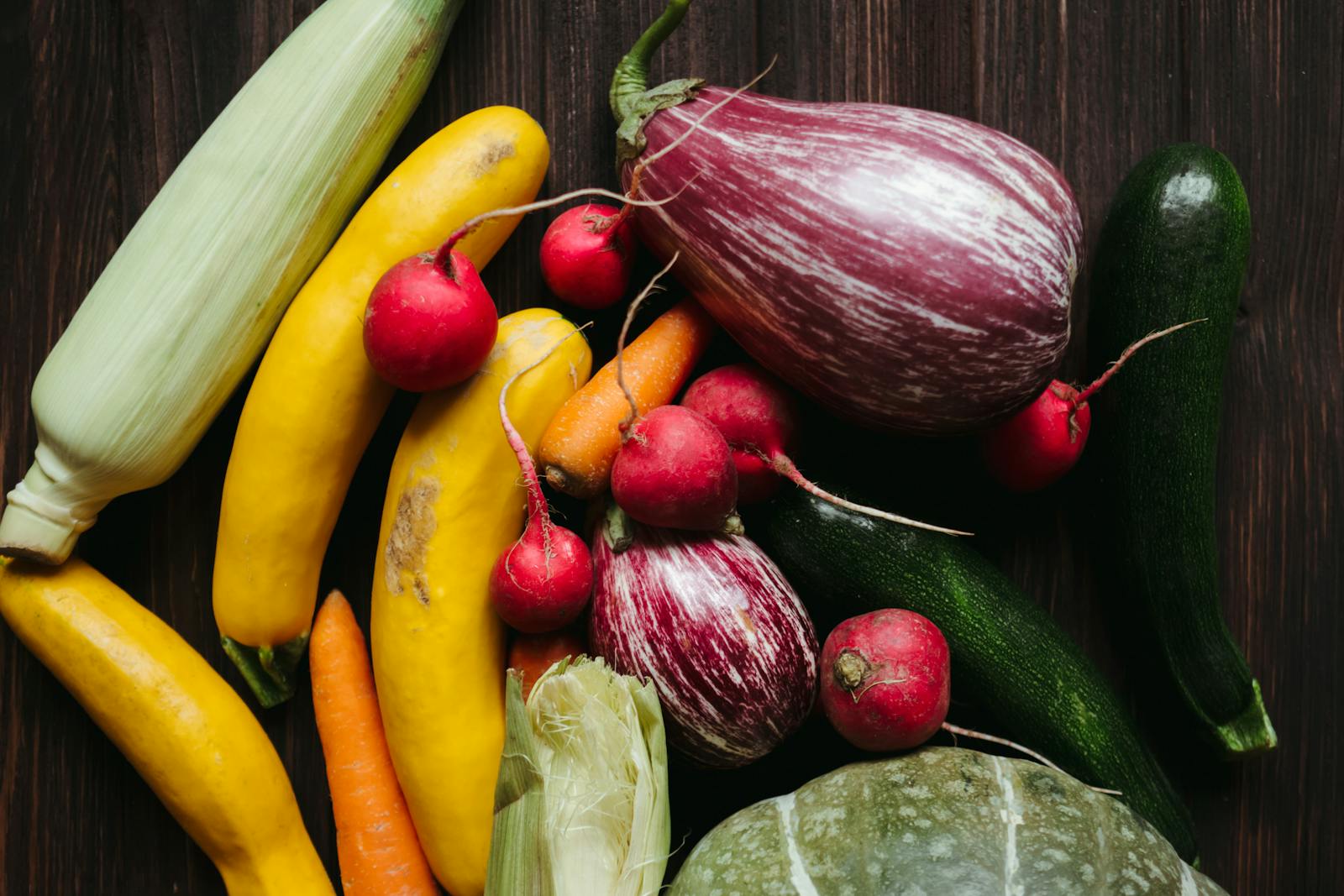 A vivid array of fresh vegetables on a dark wooden table, showcasing a healthy, organic lifestyle.