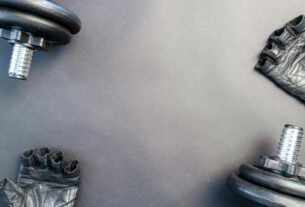 Flat lay of dumbbells and gloves on a workout surface, ready for training.