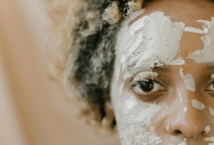 A detailed close-up photo of a person with a facial mud mask applied, focusing on their eye.