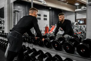 man in black long sleeve shirt and black pants carrying black dumbbell