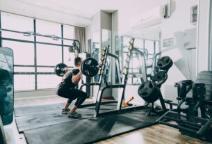 woman in black shirt and blue denim jeans sitting on black exercise equipment